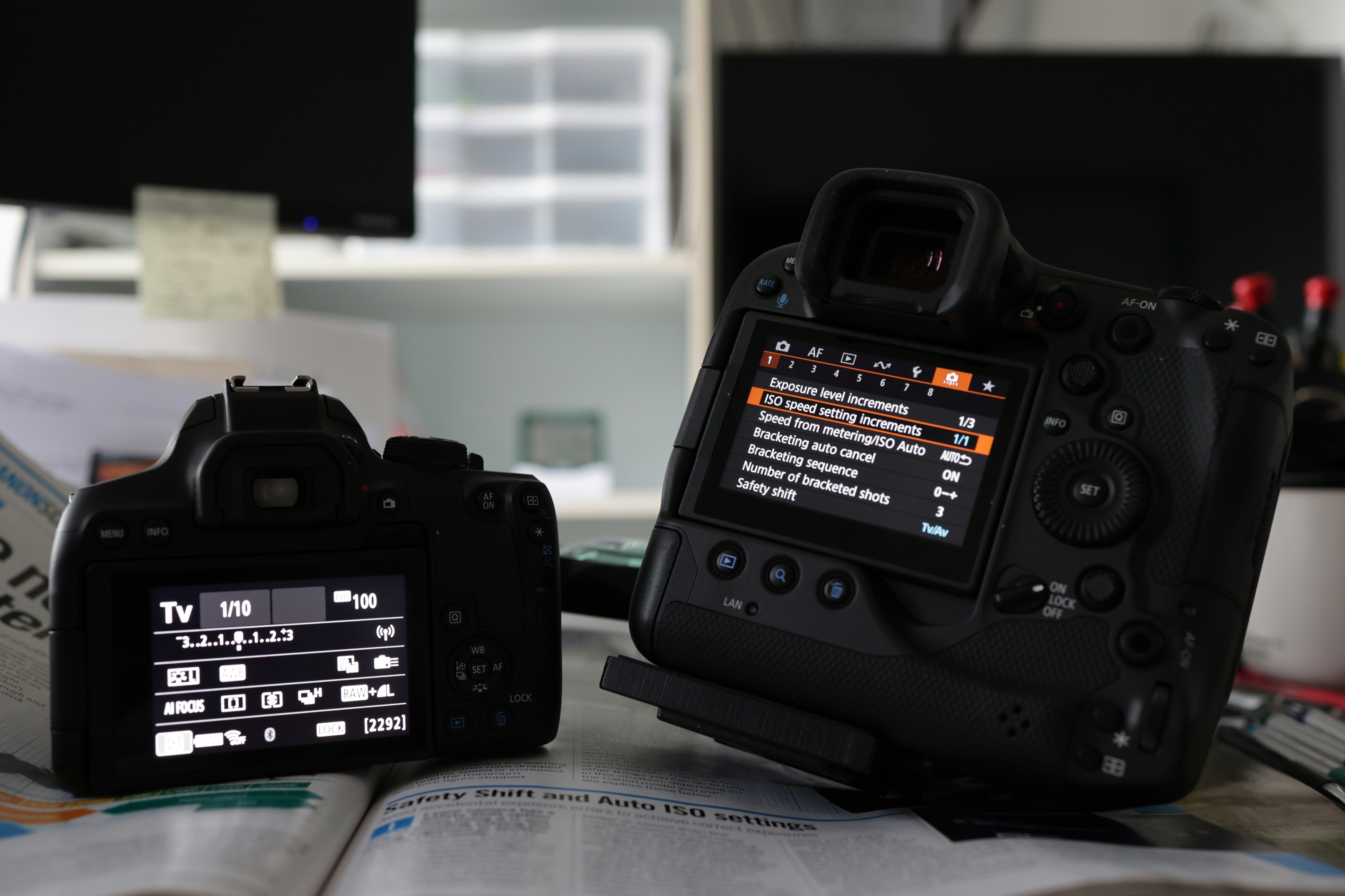 Two DSLR cameras side by side showing menu and ISO settings